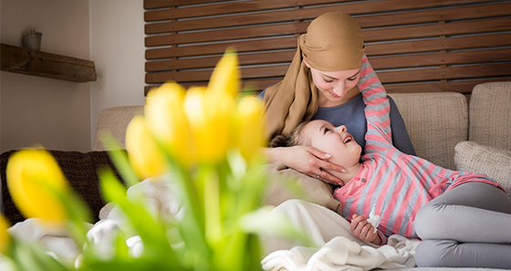 mom with headscarf and daughter in her lap looking at eaching oher and smiling