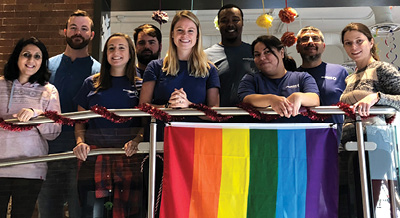 employees smiling behind a pride flag