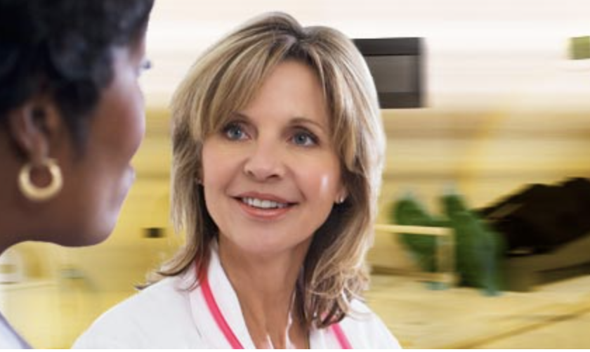 White female doctor  with lab coat blurry MRI machine in background